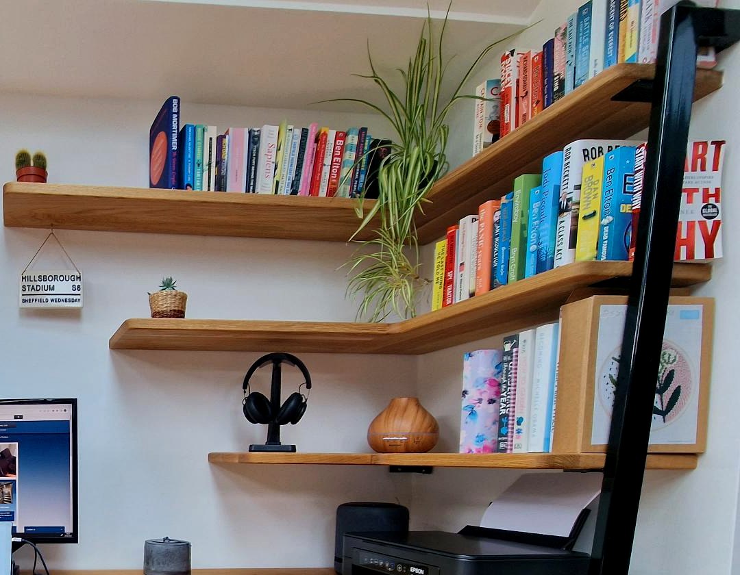 Black powder-coated fabricated steel pole supporting the oak shelves and desk